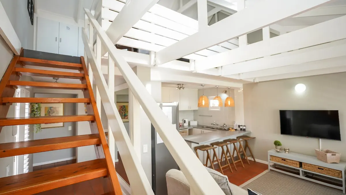 Holztreppe vorbei an der offenen Küche hinauf zum Loft-Schlafzimmer